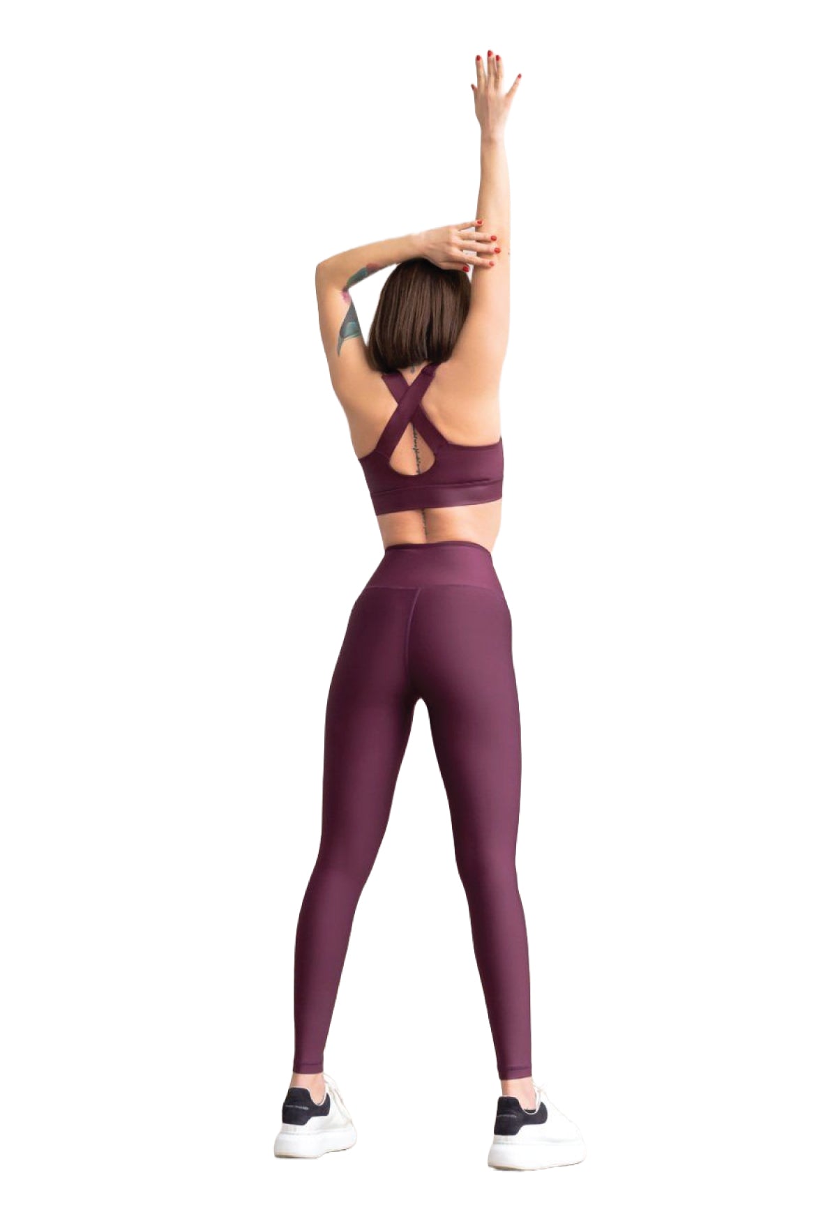 Eine Person streckt sich mit erhobenen Armen und trägt Lisminas 255 High Waist Leggings in Dunkelviolett auf weißem Hintergrund.